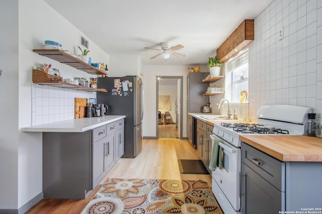 kitchen featuring tasteful backsplash, sink, gray cabinetry, stainless steel fridge, and white gas range oven