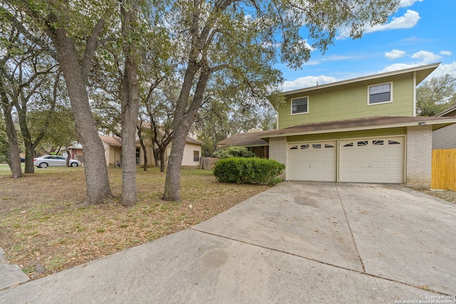 traditional home with an attached garage, fence, roof with shingles, brick siding, and driveway