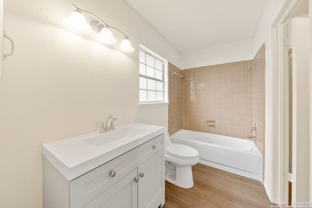 full bathroom with wood-type flooring, toilet, tiled shower / bath combo, and vanity