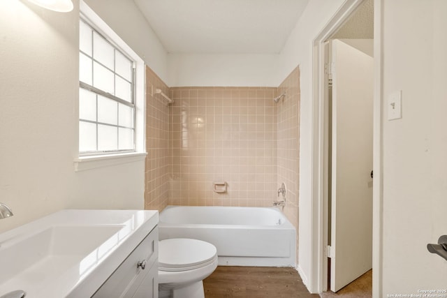 full bathroom with vanity, hardwood / wood-style flooring, tiled shower / bath combo, and toilet