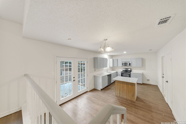 kitchen with french doors, sink, appliances with stainless steel finishes, gray cabinets, and pendant lighting