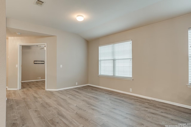 spare room featuring vaulted ceiling and light wood-type flooring