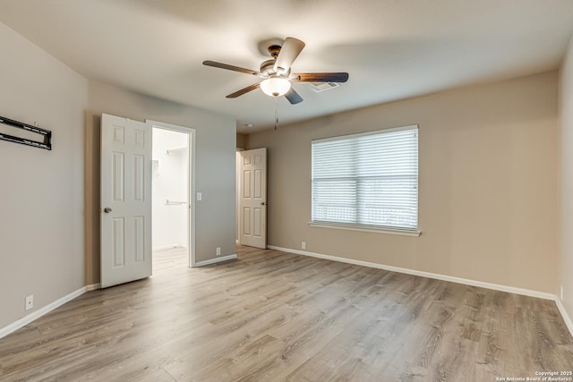 unfurnished bedroom featuring ceiling fan, a walk in closet, and light wood-type flooring