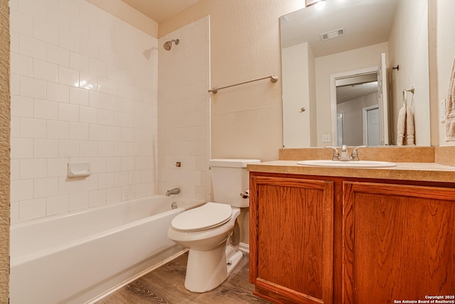 full bathroom with tiled shower / bath combo, wood-type flooring, vanity, and toilet