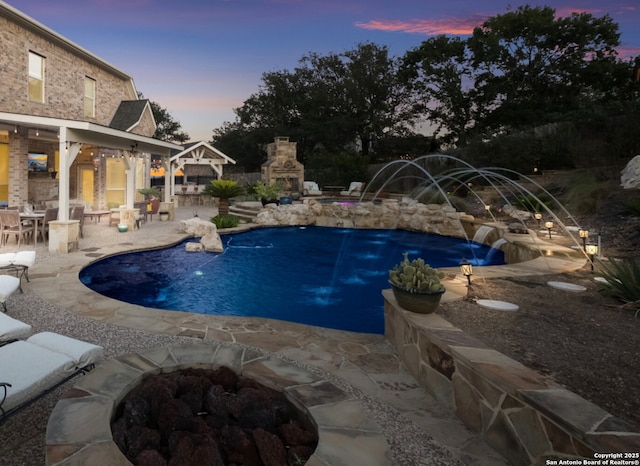 9014 Woodland Pass, Boerne, TX 78006 - pool at dusk with a patio, an outdoor fire pit, a fireplace, and an outdoor pool