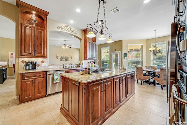 9014 Woodland Pass, Boerne, TX 78006 - kitchen featuring arched walkways, ceiling fan with notable chandelier, stainless steel appliances, tasteful backsplash, and visible vents