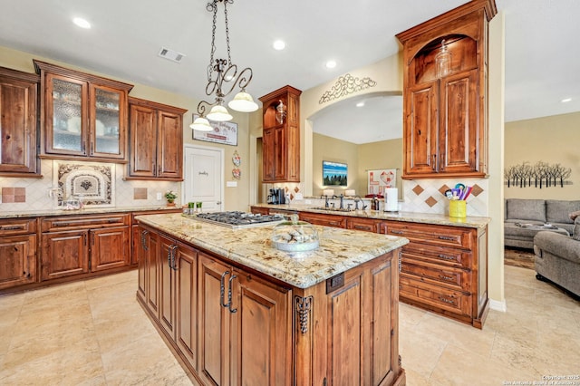 9014 Woodland Pass, Boerne, TX 78006 - kitchen with visible vents, a kitchen island, light stone counters, backsplash, and stainless steel gas stovetop