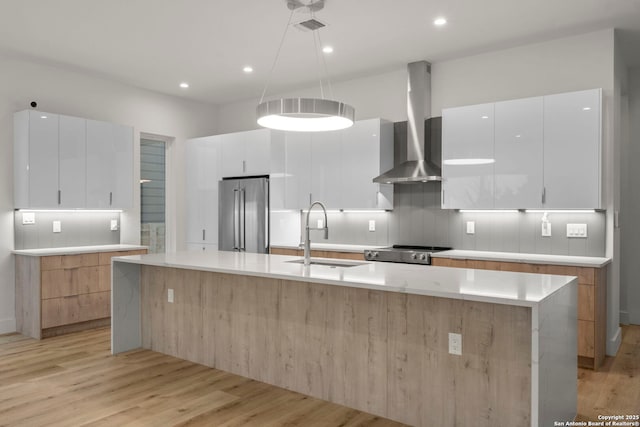 kitchen featuring white cabinetry, sink, a large island, stainless steel appliances, and wall chimney range hood