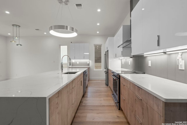 kitchen featuring a large island with sink, white cabinetry, appliances with stainless steel finishes, and decorative light fixtures