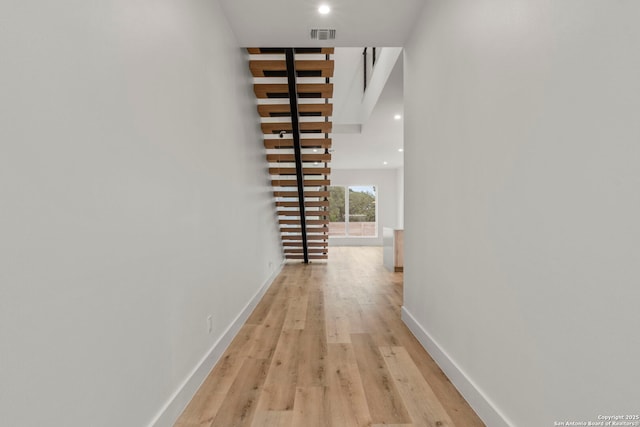 corridor with a towering ceiling and light hardwood / wood-style flooring