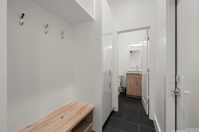 mudroom featuring dark tile patterned flooring and sink