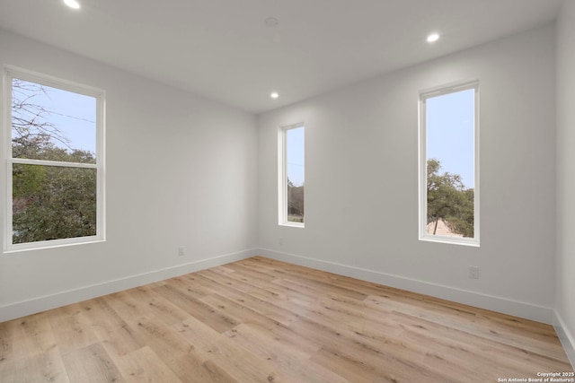 spare room featuring a healthy amount of sunlight and light hardwood / wood-style floors