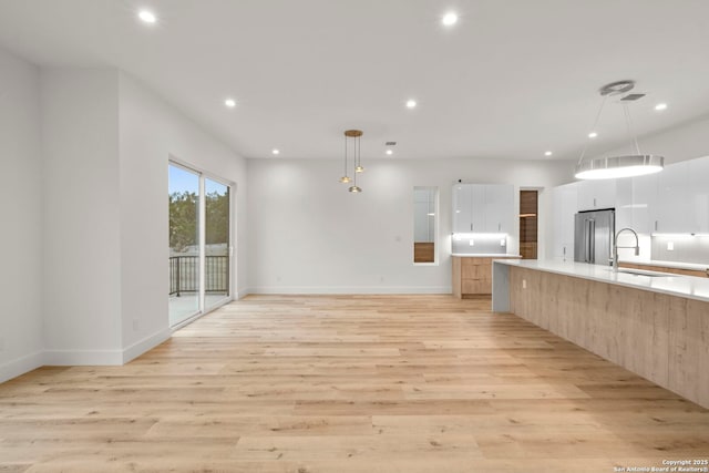 kitchen featuring pendant lighting, sink, light hardwood / wood-style flooring, and high quality fridge