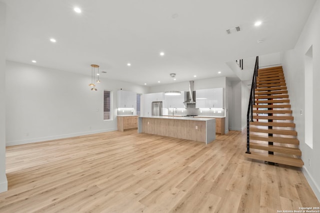 unfurnished living room featuring sink and light hardwood / wood-style floors