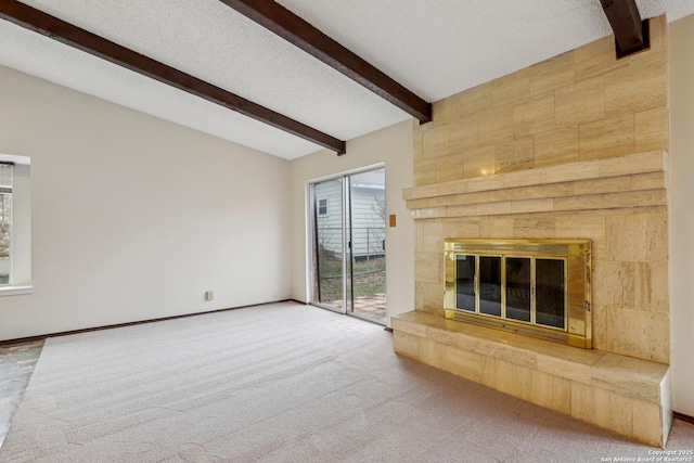 unfurnished living room with beam ceiling, a tiled fireplace, carpet, and a textured ceiling