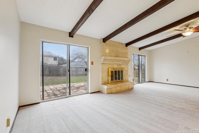 unfurnished living room with a tile fireplace, carpet floors, and a healthy amount of sunlight