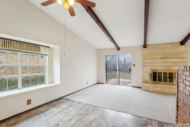 unfurnished living room featuring lofted ceiling with beams, a wealth of natural light, a textured ceiling, and a fireplace