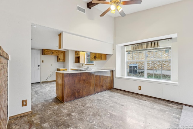 kitchen with a towering ceiling, ceiling fan, and kitchen peninsula