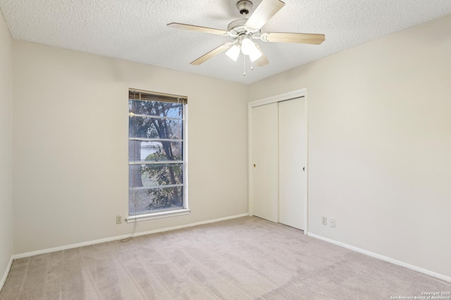 unfurnished bedroom with multiple windows, a closet, light carpet, and a textured ceiling