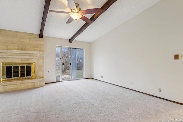 unfurnished living room featuring lofted ceiling with beams, a textured ceiling, a large fireplace, ceiling fan, and carpet