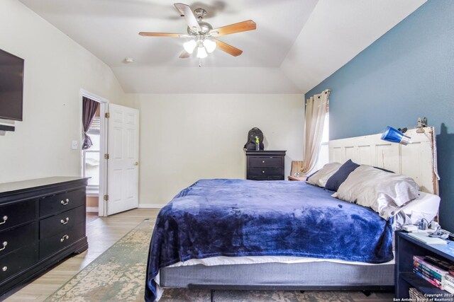 bedroom with light hardwood / wood-style flooring, vaulted ceiling, and ceiling fan