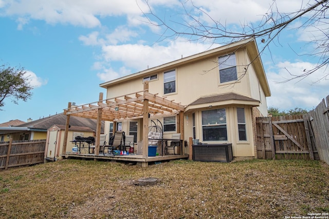 rear view of property with a wooden deck, a pergola, and a lawn