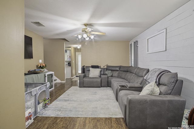 living room with dark wood-type flooring and ceiling fan