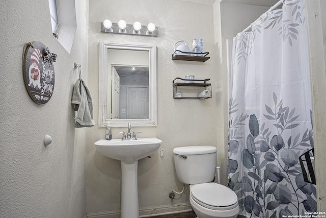 bathroom featuring sink, a shower with shower curtain, and toilet