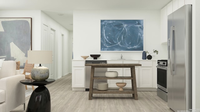 interior space featuring light wood-type flooring, stainless steel fridge, sink, and white cabinets