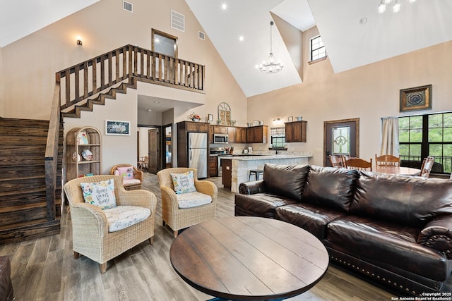 living room featuring hardwood / wood-style flooring, high vaulted ceiling, and a chandelier