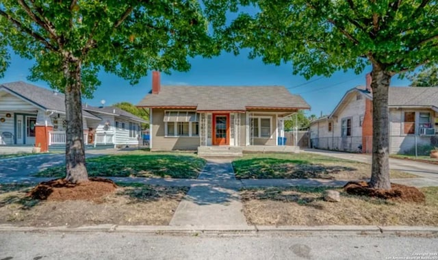 bungalow-style home with a chimney and fence