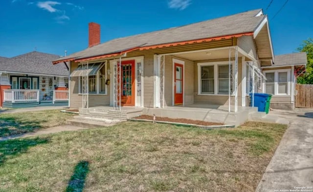 view of front of property with a front yard, covered porch, and a chimney