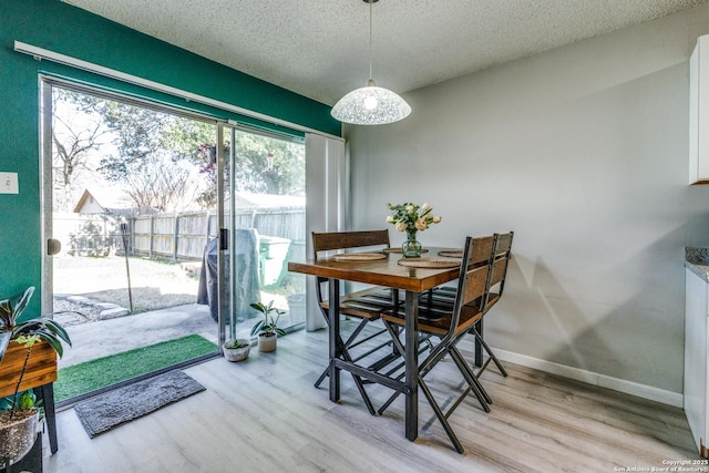 dining room with light hardwood / wood-style floors and a textured ceiling