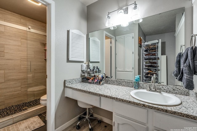 bathroom with vanity, a tile shower, and toilet