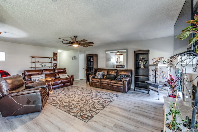 living room featuring ceiling fan, light hardwood / wood-style floors, and a textured ceiling