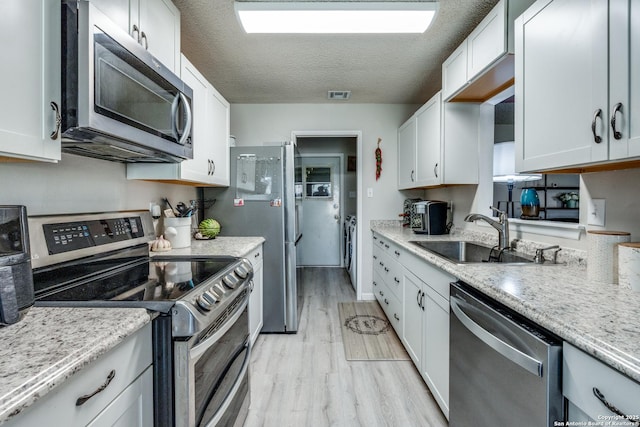 kitchen featuring sink, appliances with stainless steel finishes, light hardwood / wood-style floors, a textured ceiling, and white cabinets