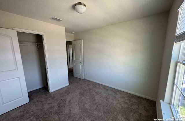 unfurnished bedroom with a closet and dark colored carpet