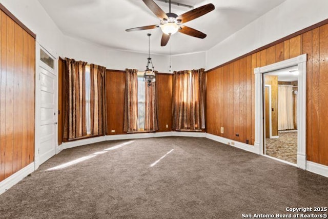 carpeted spare room with ceiling fan and wooden walls