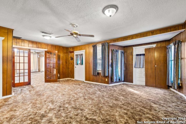 interior space featuring ceiling fan, a textured ceiling, and wood walls