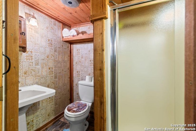 bathroom featuring a shower with door, wooden ceiling, and toilet