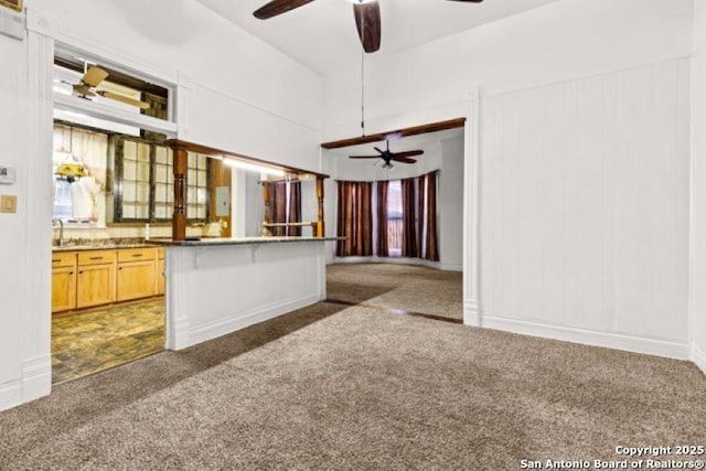 kitchen with a breakfast bar, dark colored carpet, ceiling fan, and light brown cabinets