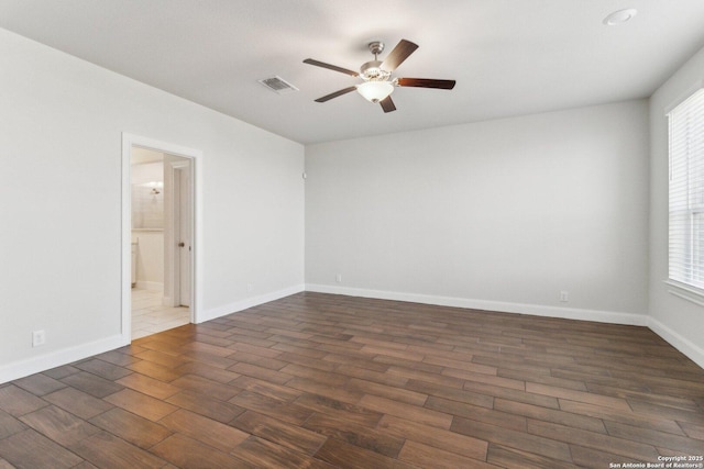 empty room with dark wood-type flooring, ceiling fan, and a wealth of natural light