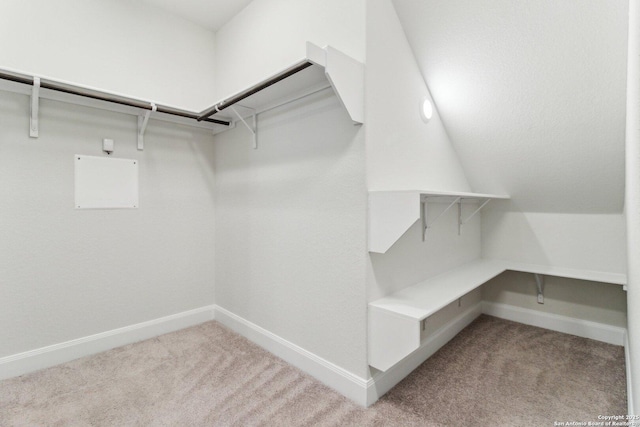 walk in closet with light carpet and vaulted ceiling