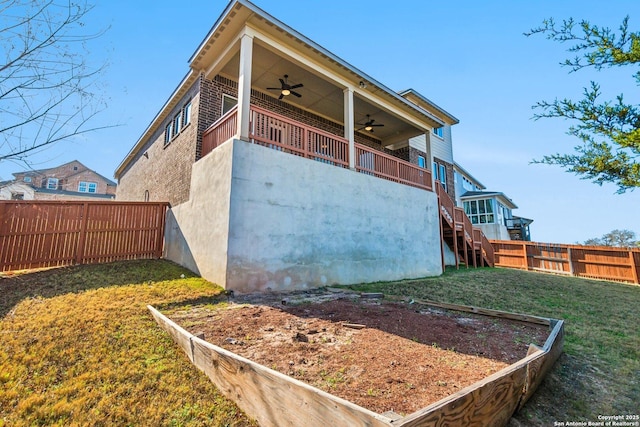 rear view of house with ceiling fan and a lawn