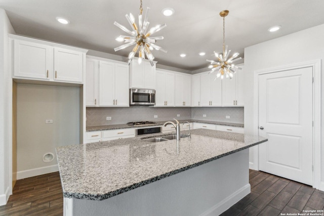 kitchen featuring an inviting chandelier, stainless steel appliances, sink, and white cabinets