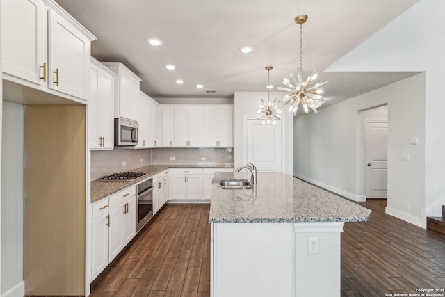 kitchen featuring sink, white cabinetry, a kitchen island with sink, stainless steel appliances, and light stone counters