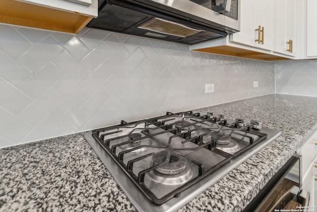 interior details featuring light stone counters, decorative backsplash, white cabinets, and appliances with stainless steel finishes