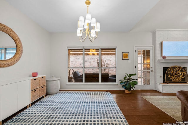 interior space with a brick fireplace, dark hardwood / wood-style floors, lofted ceiling, and a chandelier