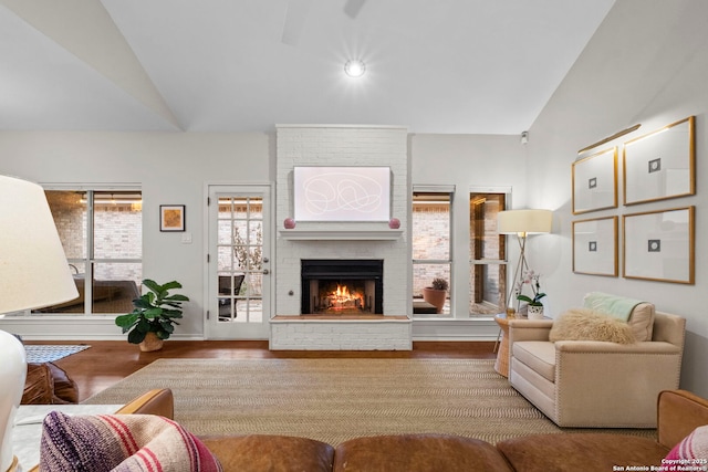 living room with lofted ceiling, a brick fireplace, and light wood-type flooring