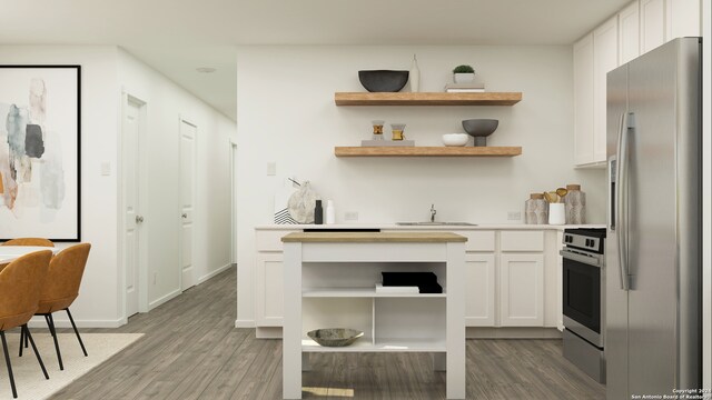 kitchen with white cabinetry, sink, stainless steel fridge, hardwood / wood-style flooring, and wall oven